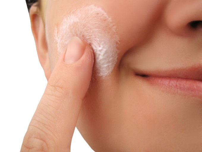 woman applies moisturizer onto face