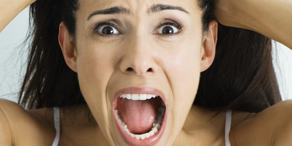 Woman pulling hair and screaming at camera, portrait